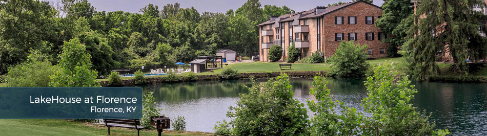 Apartment community by a pond with surrounding greenery